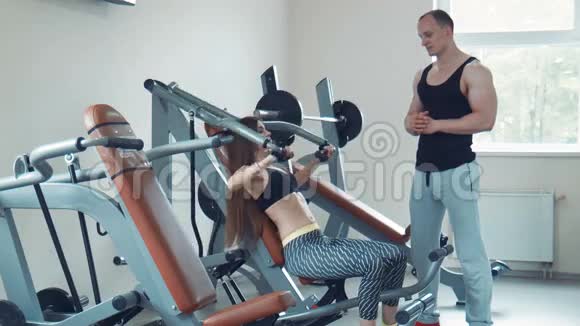 教练看着女人在健身房里做板凳压视频的预览图