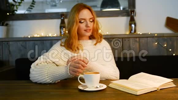 年轻漂亮的女人正在咖啡馆看书她微笑着享受咖啡的香气视频的预览图