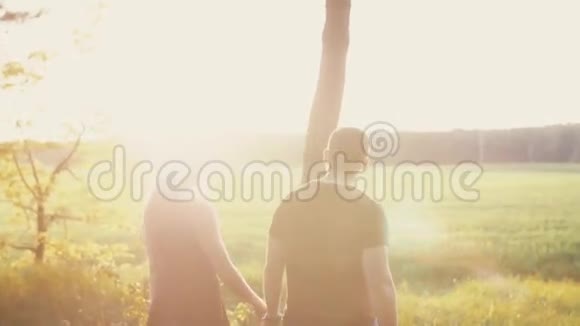 恋人们在日落时漫步在大自然中男人和女人拥抱和亲吻阳光下的田野后退慢点稳拍视频的预览图