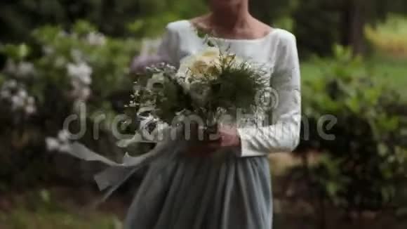 在公园里年轻时尚的新娘手挽手手捧一束美丽的鲜花视频的预览图