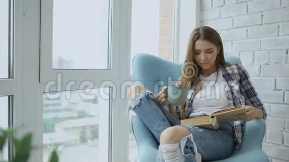 年轻迷人的女人在现代阁楼公寓的阳台上看书喝咖啡视频的预览图