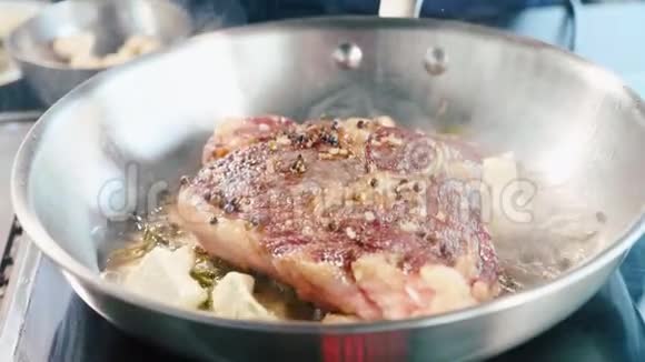 肉牛排加调味料和香草在煎锅上嘶嘶作响特写视频的预览图