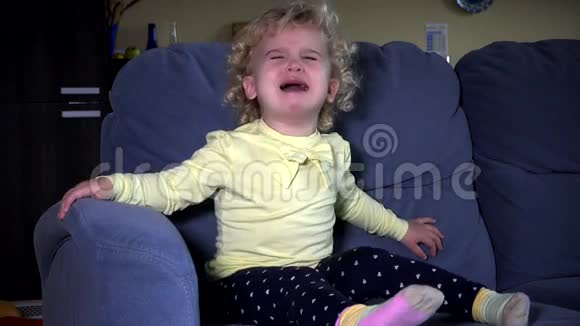坐在沙发上哭的可爱的小女孩视频的预览图