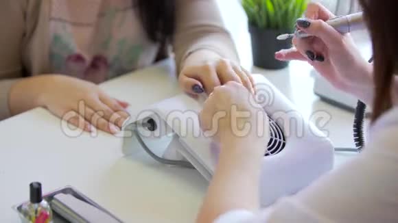 师傅做五金美甲美甲医生正在用电指甲锉钻对女性手指进行美甲视频的预览图