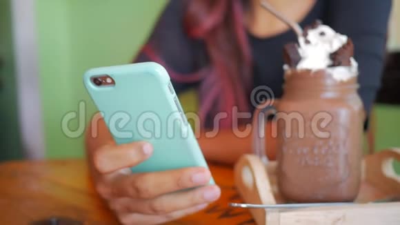 年轻女性使用智能手机在咖啡厅与甜巧克力甜点背景视频的预览图