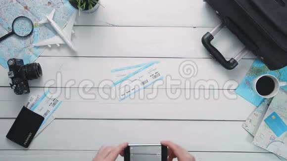 顶景旅客在白色的木桌上用智能手机拍照机票视频的预览图
