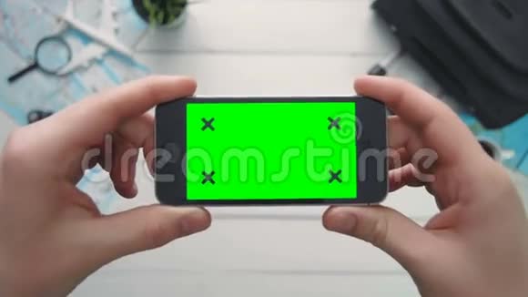 顶视图旅行者手拿着电话水平绿色屏幕和跟踪点白色木桌视频的预览图