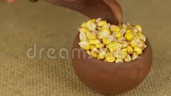用勺子把旋转的陶罐里的玉米粒倒掉视频的预览图