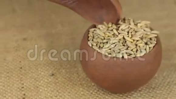 用勺子把旋转的泥锅里的黑麦粒倒掉视频的预览图