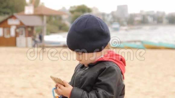 一个男孩在智能手机上按下按钮转动告诉什么手里拿着五颜六色的玩具戒指视频的预览图