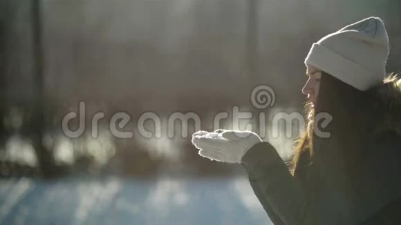 风云中的神奇女侠是在早晨站在白雪皑皑的冬季公园里用手吹着雪花视频的预览图