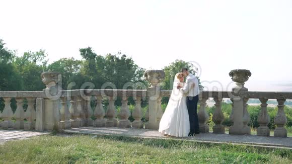 快乐的新婚夫妇拥抱亲吻城堡的阳台4K视频的预览图