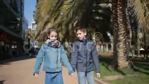 两个孩子兄妹双胞胎在小巷的公园里散步视频的预览图