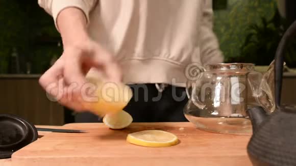 女性手的特写是用柠檬把一把刀切成碎片挤在木桌上泡茶视频的预览图
