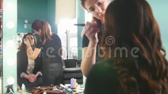 专业造型师女在美容院为镜前的年轻女子化妆视频的预览图