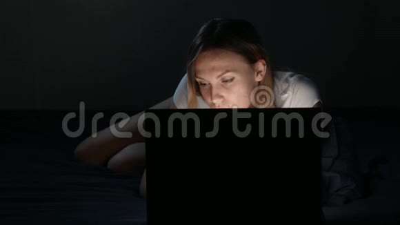 漂亮的女孩躺在卧室里手提电脑视频的预览图