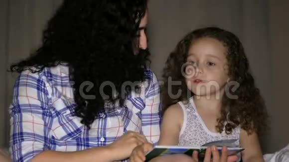 妈妈和一个漂亮的小女儿一起带着一个童话故事的情节读了一遍视频的预览图
