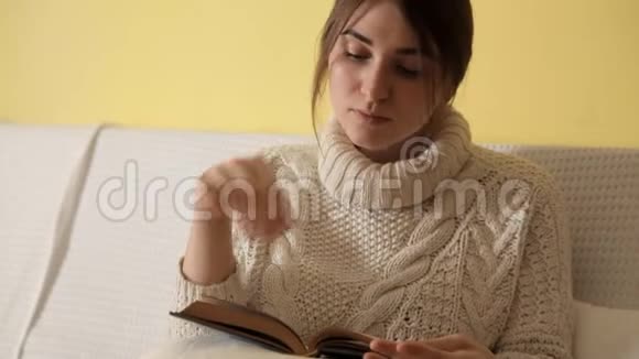 冬天晚上在家穿着舒适温暖毛衣的小女孩看书视频的预览图