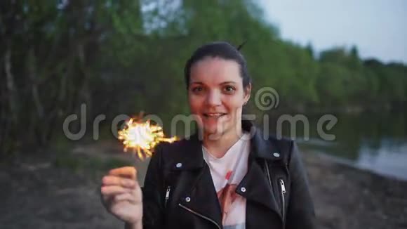 在海滩派对上带着火花的年轻微笑女人的肖像视频的预览图