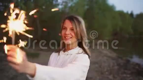 在海滩派对上带着火花的年轻微笑女人的肖像视频的预览图