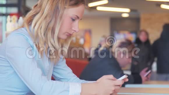 快乐的年轻女人坐在一张桌子上用手机喝咖啡视频的预览图