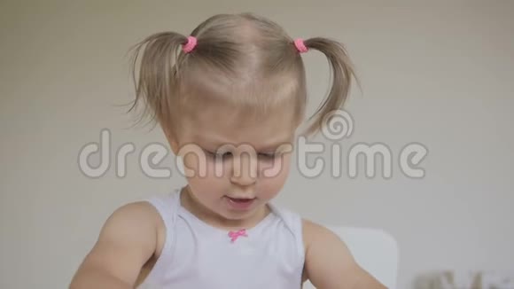 一个小女孩坐在一个明亮的房间的桌子旁雕刻一个粉红色的塑料雕像视频的预览图