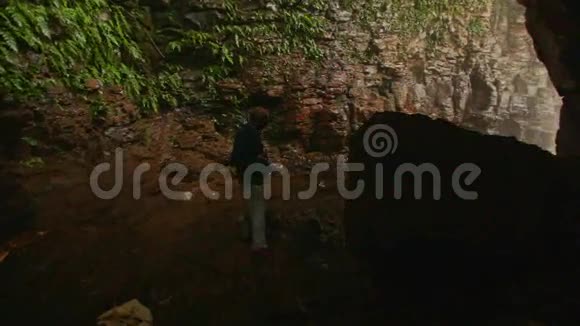 老人在黑暗洞穴中漫步从瀑布下的淡雾出口视频的预览图