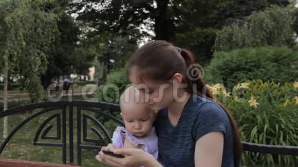 一个年轻的女人向一个抱着她的小女孩展示手机屏幕小女孩把东西推到上面视频的预览图