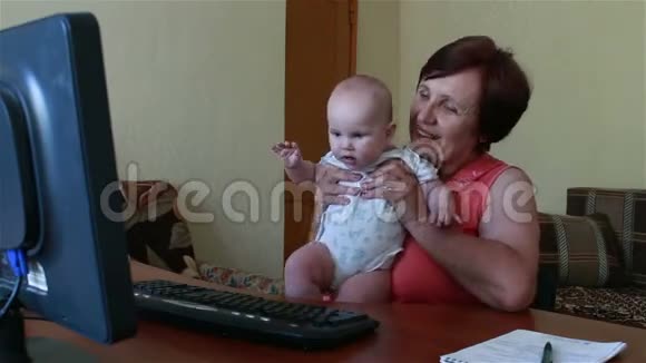 一位老妇人在电脑上打电话婴儿正在表演视频的预览图