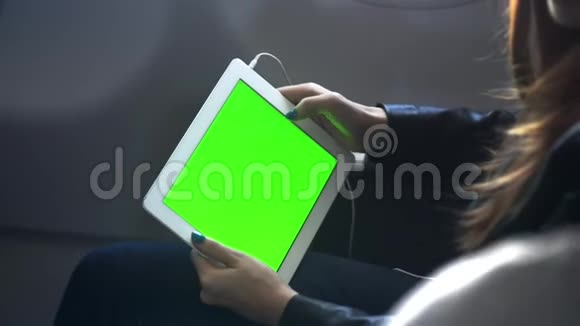 女人手里拿着平板电脑坐在飞机上视频的预览图