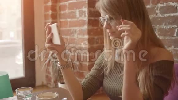 年轻的微笑女人在咖啡店吃早餐时用智能手机进行视频对话视频的预览图