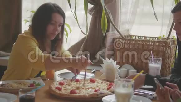 少女在咖啡馆吃披萨快餐慢动作视频孩子们吃比萨饼吃美味的比萨饼人的公司视频的预览图