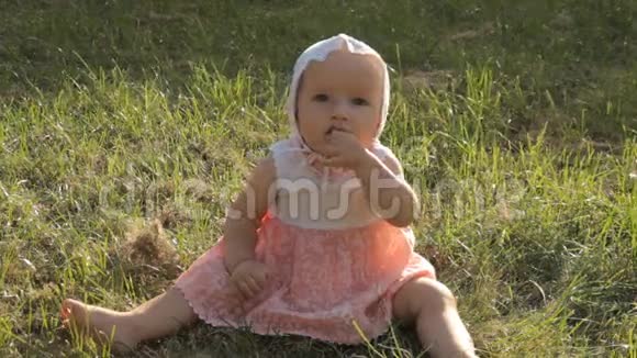 一个年轻的女孩在草地上一边一边摇晃嘴里含着半只手视频的预览图