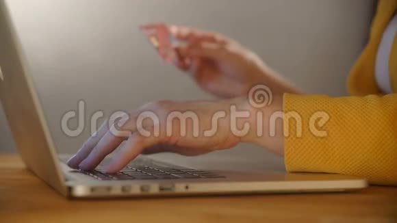 女人手拿着信用卡用电脑键盘上网购物视频的预览图