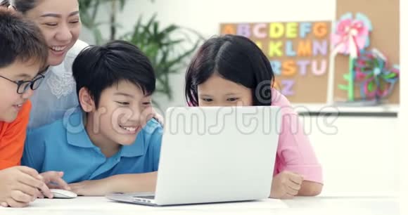 亚洲女教师和可爱的亚洲儿童一起使用笔记本电脑视频的预览图
