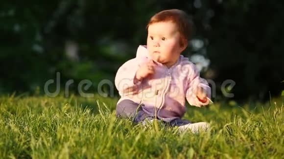 日落时分快乐的小女孩坐在公园的绿草上视频的预览图