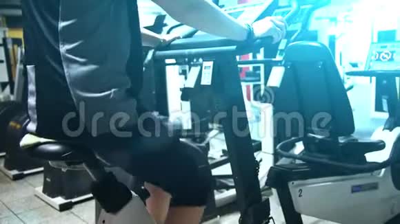 一个在健身房里骑固定自行车锻炼的女孩视频的预览图