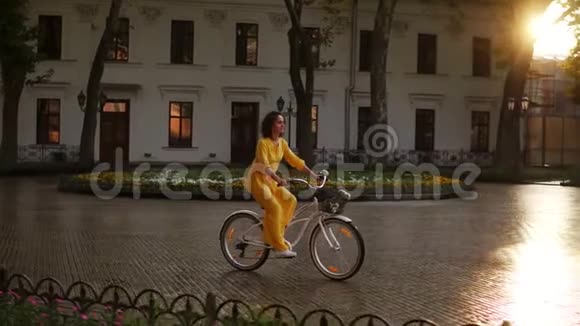 黎明时分年轻女子骑着一辆自行车在市中心放着篮子和鲜花享受着她的时光视频的预览图