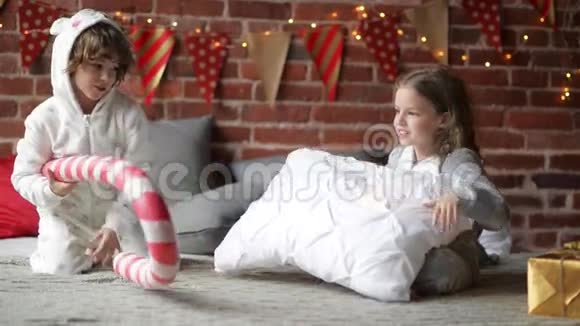 穿着温暖的圣诞睡衣在家里抱着枕头打架兄弟姐妹一起在圣诞节玩耍的兄弟姐妹视频的预览图