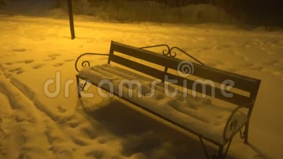 雪上公园夜晚有长凳和灯光下雪下雪视频的预览图