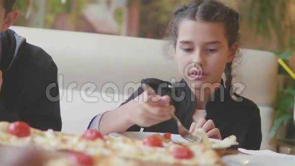 少女在咖啡厅慢动作视频里吃披萨孩子们吃比萨饼吃美味的比萨饼与生活方式有关的人视频的预览图