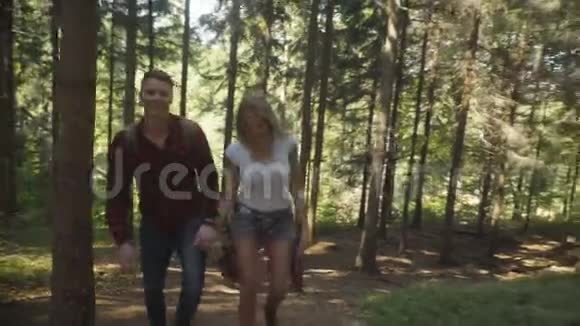 阳光明媚的日子里一对微笑的夫妇在树林里散步视频的预览图