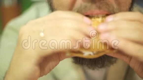 一个长着胡子的白种人晚上坐在夏季咖啡馆的一张桌子上吃汉堡包快关门视频的预览图