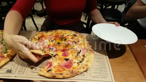 女性手在盘子上切块披萨视频的预览图