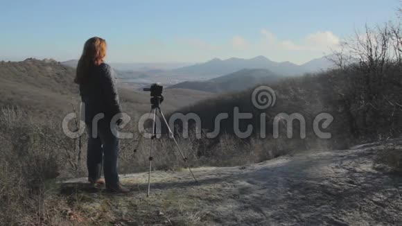 女人用三脚架上的摄像机拍摄风景视频的预览图
