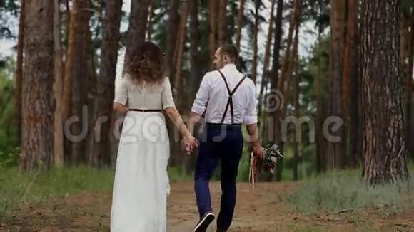 这对夫妇在一片松林里消磨时光然后转身拥抱对方在高大树木的背景下视频的预览图