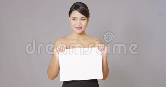 微笑的女人看着手中的白牌视频的预览图