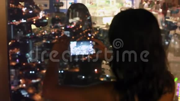 一位年轻女子在槟城的一座摩天大楼顶上用智能手机拍照照片模糊视频的预览图