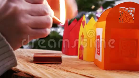 在圣诞树前用火柴点燃蜡烛4k视频的预览图