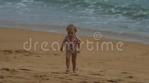 在沙滩上散步的金发小女孩视频的预览图
